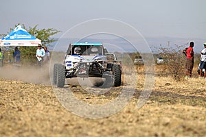 Speeding white Chenowth rally car front view